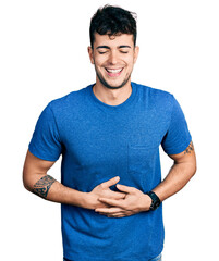 Poster - Young hispanic man wearing casual t shirt smiling and laughing hard out loud because funny crazy joke with hands on body.