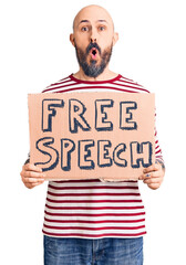 Sticker - Young handsome man holding free speech banner scared and amazed with open mouth for surprise, disbelief face