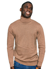 Wall Mural - Young african american man wearing casual winter sweater looking away to side with smile on face, natural expression. laughing confident.