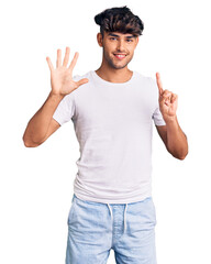 Sticker - Young hispanic man wearing casual clothes showing and pointing up with fingers number six while smiling confident and happy.