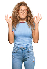 Poster - Beautiful caucasian teenager girl wearing casual clothes and glasses relax and smiling with eyes closed doing meditation gesture with fingers. yoga concept.