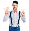 © Krakenimages.com - Hispanic man with beard wearing hipster look with bow tie and suspenders showing and pointing up with fingers number eight while smiling confident and happy.