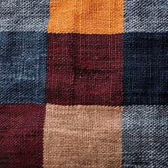 Colorful patchwork fabric with textured squares in various shades of blue, orange, maroon, and beige. Ideal for textile design.