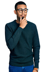 Poster - Young african american man wearing casual clothes and glasses with hand on chin thinking about question, pensive expression. smiling with thoughtful face. doubt concept.