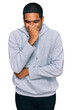 © Krakenimages.com - Young handsome hispanic man wearing casual sweatshirt smelling something stinky and disgusting, intolerable smell, holding breath with fingers on nose. bad smell