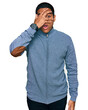 © Krakenimages.com - Young handsome hispanic man wearing casual sweatshirt peeking in shock covering face and eyes with hand, looking through fingers with embarrassed expression.