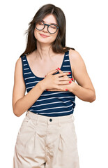 Wall Mural - Young beautiful caucasian girl wearing casual clothes and glasses smiling with hands on chest with closed eyes and grateful gesture on face. health concept.