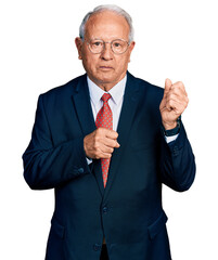 Canvas Print - Senior man with grey hair wearing business suit and glasses ready to fight with fist defense gesture, angry and upset face, afraid of problem