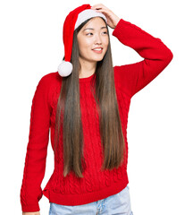 Canvas Print - Young chinese woman wearing christmas hat smiling confident touching hair with hand up gesture, posing attractive and fashionable