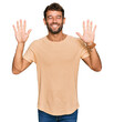 © Krakenimages.com - Handsome young man with beard wearing casual tshirt showing and pointing up with fingers number ten while smiling confident and happy.