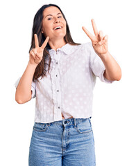 Wall Mural - Young beautiful brunette woman wearing casual shirt smiling looking to the camera showing fingers doing victory sign. number two.