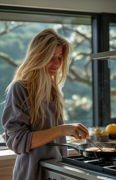 A young blonde woman cooks pancakes on a modern black ceramic hob in her kitchen