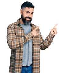 Wall Mural - Hispanic man with beard wearing casual shirt smiling and looking at the camera pointing with two hands and fingers to the side.