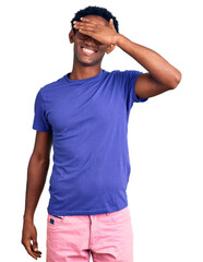 Wall Mural - African handsome man wearing casual clothes and glasses smiling and laughing with hand on face covering eyes for surprise. blind concept.