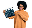 © Krakenimages.com - Young african american woman holding video film clapboard smiling happy pointing with hand and finger