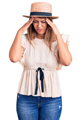 Wall Mural - Young beautiful woman wearing summer hat and t-shirt with hand on head for pain in head because stress. suffering migraine.