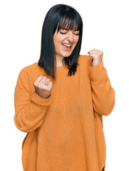 Poster - Young hispanic woman wearing casual clothes celebrating surprised and amazed for success with arms raised and eyes closed. winner concept.