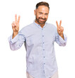 © Krakenimages.com - Handsome middle age man wearing business shirt smiling looking to the camera showing fingers doing victory sign. number two.