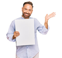 Sticker - Handsome middle age man holding blank empty banner celebrating victory with happy smile and winner expression with raised hands