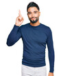 © Krakenimages.com - Young man with beard wearing casual blue winter sweater pointing finger up with successful idea. exited and happy. number one.