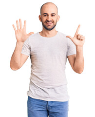 Canvas Print - Young handsome man wearing casual t shirt showing and pointing up with fingers number seven while smiling confident and happy.