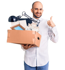 Wall Mural - Young handsome man fired holding box smiling happy and positive, thumb up doing excellent and approval sign