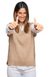 © Krakenimages.com - Young woman wearing casual clothes approving doing positive gesture with hand, thumbs up smiling and happy for success. winner gesture.