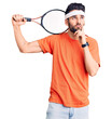 © Krakenimages.com - Young handsome man with beard playing tennis holding racket serious face thinking about question with hand on chin, thoughtful about confusing idea
