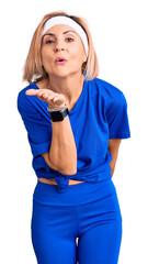 Poster - Young blonde woman wearing sportswear looking at the camera blowing a kiss with hand on air being lovely and sexy. love expression.