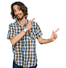 Wall Mural - Young hispanic man wearing casual clothes smiling and looking at the camera pointing with two hands and fingers to the side.