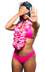 Wall Mural - Beautiful hispanic woman wearing bikini and hawaiian lei covering eyes with hands and doing stop gesture with sad and fear expression. embarrassed and negative concept.