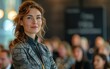 © imagineRbc - A confident female business speaker delivers a presentation to a large audience at a conference