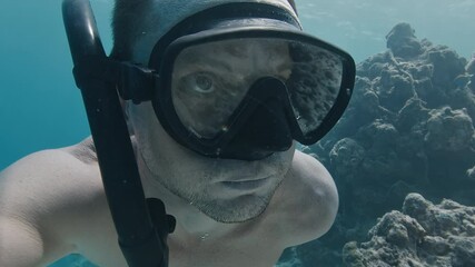 Sticker - Man swims underwater in the sea with coral reef reflecting in the mask