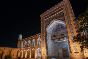 Wall Mural - A large building with a blue archway and a clock tower. The building is lit up at night