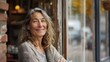 © maikuto - Portrait of a smiling mature woman standing confidently outside a cozy cafe, exuding warmth and welcoming energy in a casual setting.