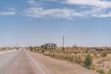 Wall Mural - A road with a house in the distance. The sky is blue and there are no clouds