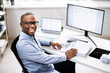 © Andrey Popov - Top African-American Tax Advisor Smiling While Multitasking at His Desk