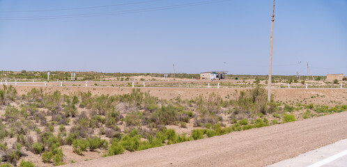 Wall Mural - A barren desert landscape with a dirt road and a few poles. The sky is clear and blue