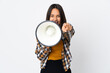 © luismolinero - Young latin woman isolated on white background shouting through a megaphone to announce something while pointing to the front
