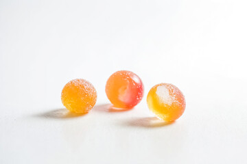 Poster - Three Orange and Yellow Candy Balls on White Background