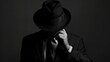 © atipong - Silhouette of Man in suit hiding face behind his hat isolated on dark background. secret and incognito concept