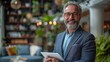 © Photolife   - confident smiling middle-aged Caucasian businessman in a business suit with a tablet computer in his hands while in the office looking at the camera