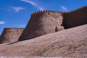 Wall Mural - A large stone wall with a small building in the middle. The sky is blue and there are no clouds