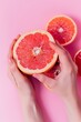 © World of AI - hands peeling a grapefruit, revealing the juicy,, pink background