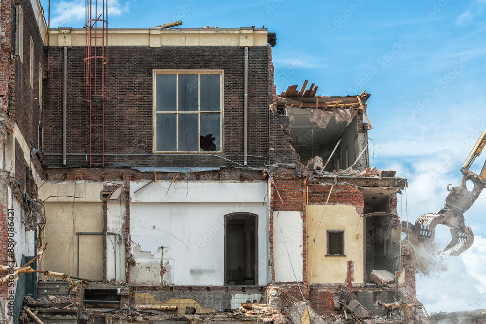 former office building is being demolished by a demolition machine