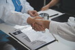 © Sirikarn Rinruesee - Doctor handshake and partnership in healthcare, medicine or trust for collaboration, unity or support.Team of medical experts shaking hands in teamwork for or success in hospital