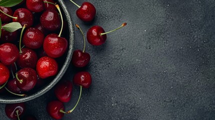 Wall Mural - A close-up of a bowl filled with ripe cherries on dark grey background, copy space