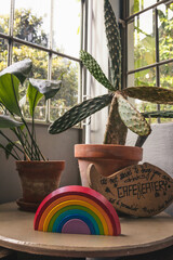 Close up shots of kids homemade toy composed of a rainbow, a cafe sign and two plants populating the out of focus background in front of a window