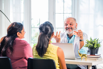 Wall Mural - Indian asian elderly, old or experienced male doctor with Woman and kid patient in clinic