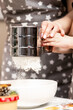 © Ekaterina - Metal cup sieve in the hands of a child, sifting flour, the process of making dough at Christmas.